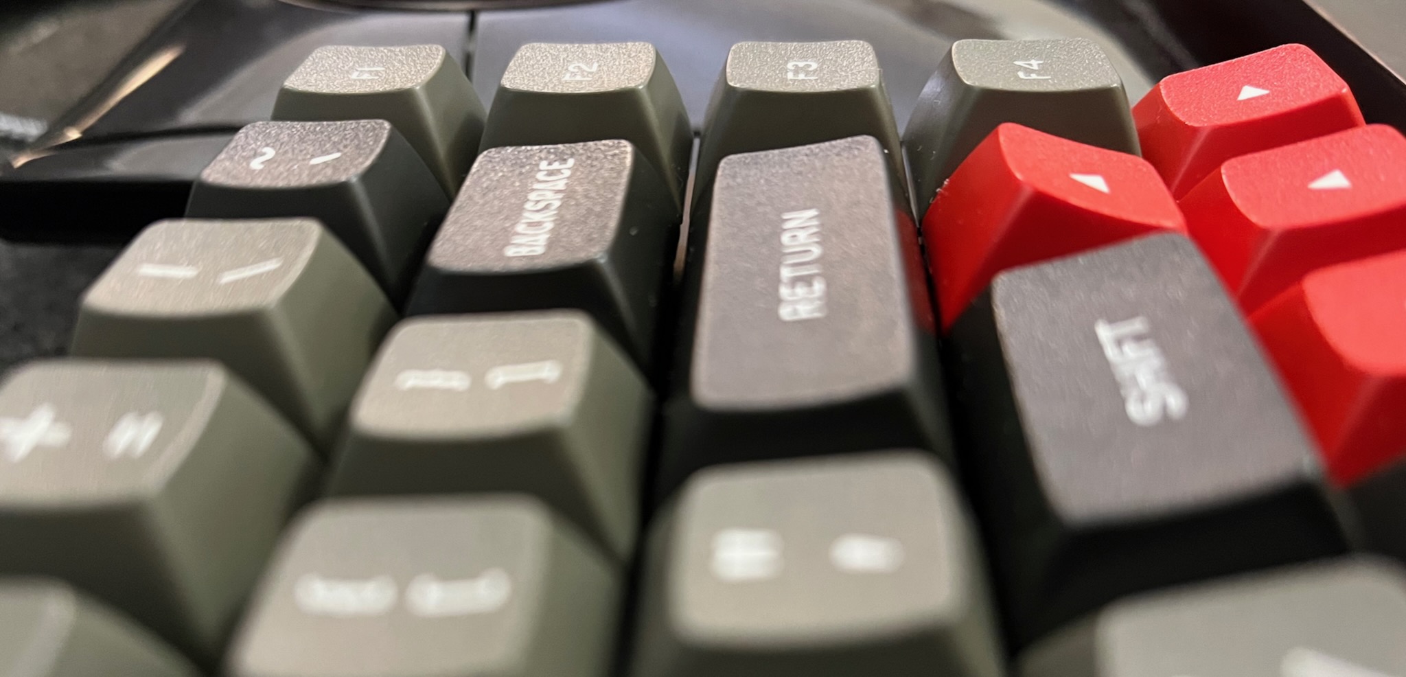 a closeup of Keybird69 looking along its RETURN key towards the column of F keys and arrow keys; the angle of the F key next to RETURN is noticably different, and the angle of the up arrow key is outrageously jaunty