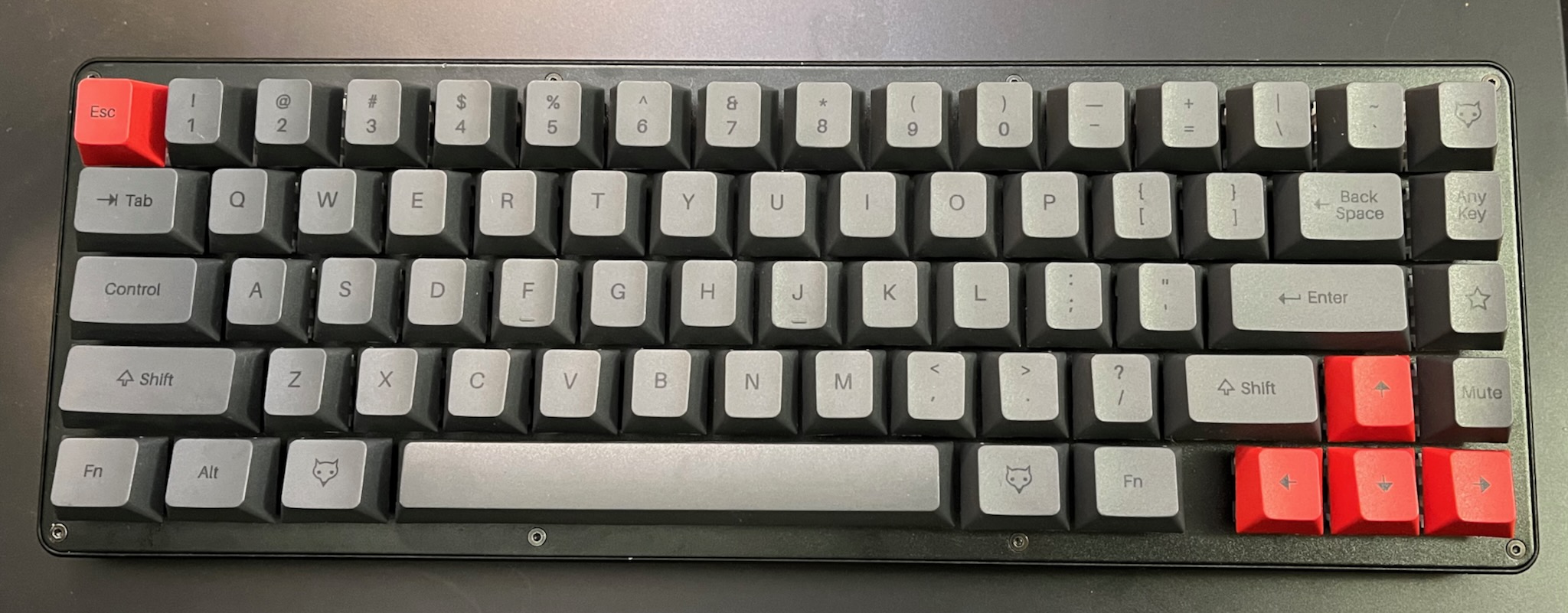 a 65% keyboard in shades of grey with red escape and arrow keys